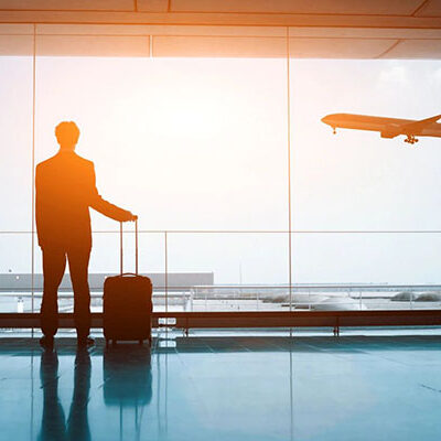 The Aeronautical Institute A man standing in front of an airport window with his luggage.